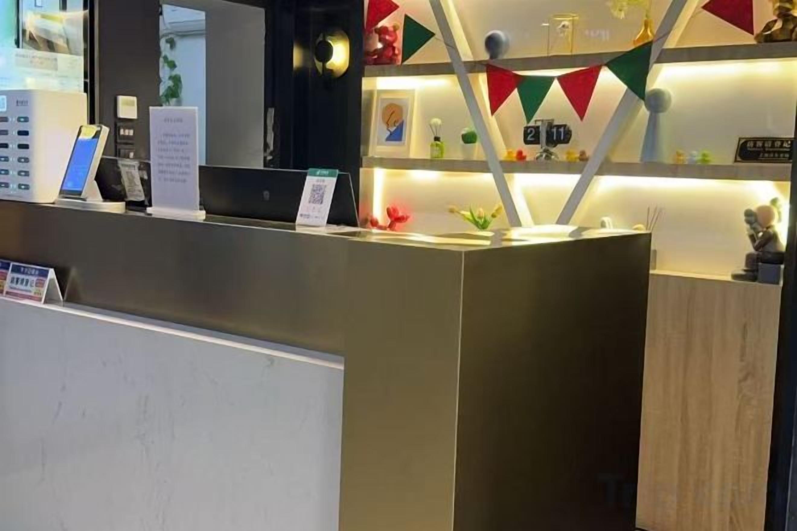 Uma receção de design moderno, com um ecrã digital e uma pequena planta.