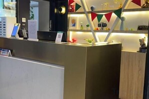 Un mostrador de recepción de diseño moderno, con una pantalla digital y una pequeña planta.