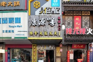 A street view with various storefronts, including a pharmacy, a convenience store, and a restaurant. - 100 Inn (Zhoupu Wanda) (Shanghai)