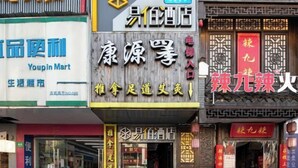 A row of storefronts with various signs, including one for a Youpin Mart and another for a hotel. - 100 Inn (Zhoupu Wanda) (Shanghai)