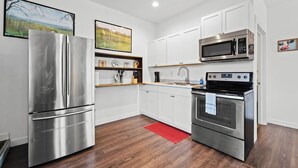 A modern kitchen with stainless steel appliances, white cabinetry, and a red rug.