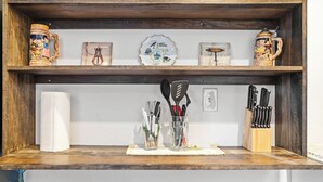 A kitchen shelf with decorative items, a map, and kitchen utensils.