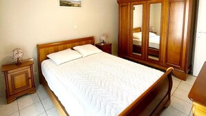 Un dormitorio con cama de madera, mesita de noche, armario y una lámpara en el techo.
