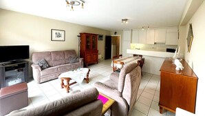 Una sala de estar con un sofá, una mesa de centro, un televisor y un mueble.