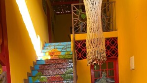 A staircase with colorful mosaic steps, a red door with a sign, and a hanging macrame piece. - Casa Artística Pousada Leão (Maceio)