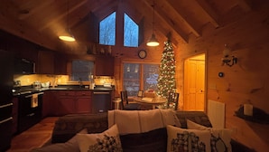 A cozy cabin interior with a wooden interior, a dining area, a kitchen, and a Christmas tree. - Romantic Mountain view Cabin with Indoor/Outdoor Spa House + Sauna (Ellijay)