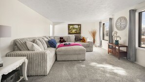 A living room with a sectional sofa, a small table, and a decorative wall piece.