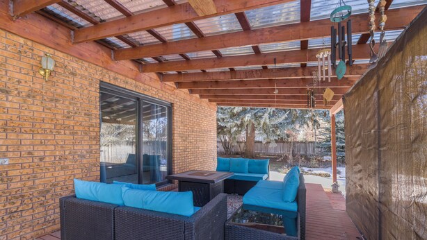 An outdoor patio with wicker furniture and a glass door leading to a covered area.