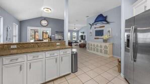 A spacious kitchen with white cabinets, a granite countertop, and a stainless steel refrigerator. - Seaside Canal Retreat: Renovated Home with Private Dock Near Port Aransas (Corpus Christi)