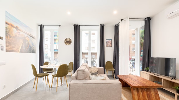Un salon moderne comprenant un canapé, une table à manger, des chaises et un téléviseur.