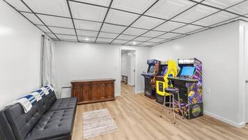 Ein Zimmer mit einer schwarzen Ledersofa, einem Holzschrank und zwei Spielautomaten.
