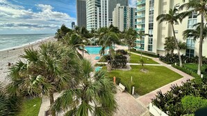 A beachfront hotel with a pool, palm trees, and ocean views. - Ocean View Condo, Direct Beach Access, Beach Gear & Cleaning Included (Hollywood)