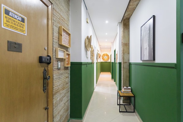 A hallway with green walls, a wooden door, and a sign indicating a silent period.
