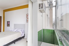 A bedroom with a bed, a window, and a green-tiled wall.