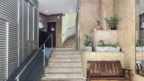 Een hotel lobby met een marmeren trap, een houten bank en potplanten.