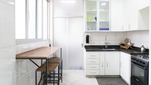 Een moderne keuken met witte kasten, een houten tafel en een zwart fornuis.
