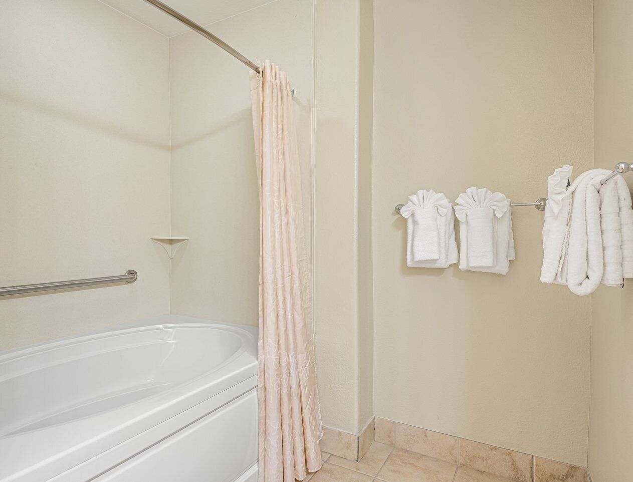 A bathroom with a bathtub, a shower curtain, and towels hanging on a rack.
