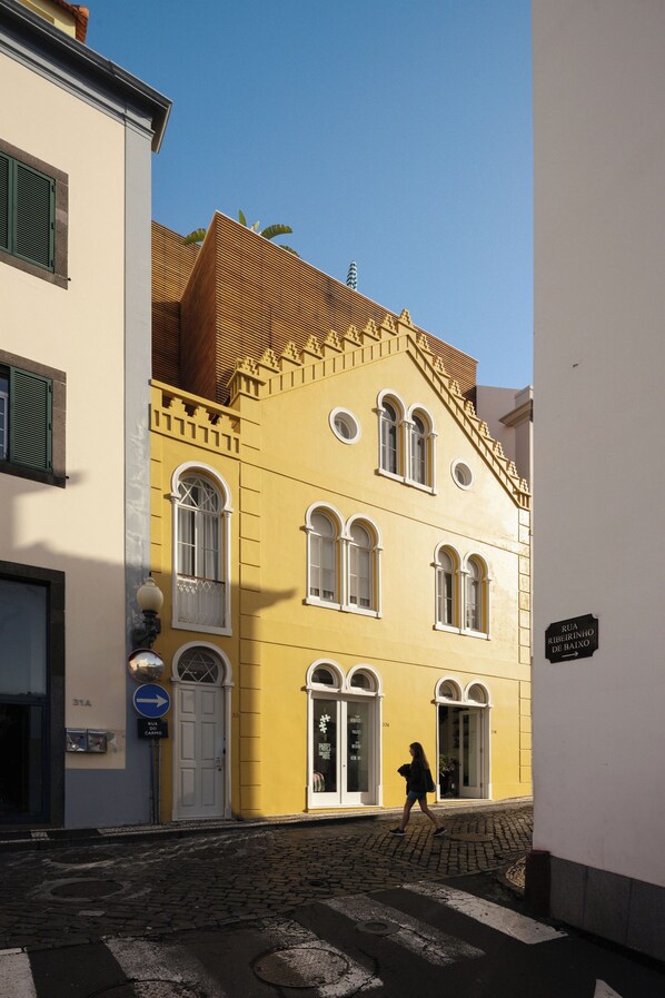 Un edificio amarillo con ventanas arqueadas y una puerta blanca, con la leyenda
