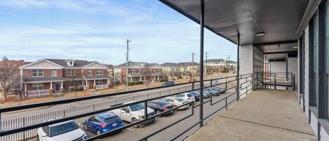 Un balcon donnant sur un parking et des immeubles d’habitation.
