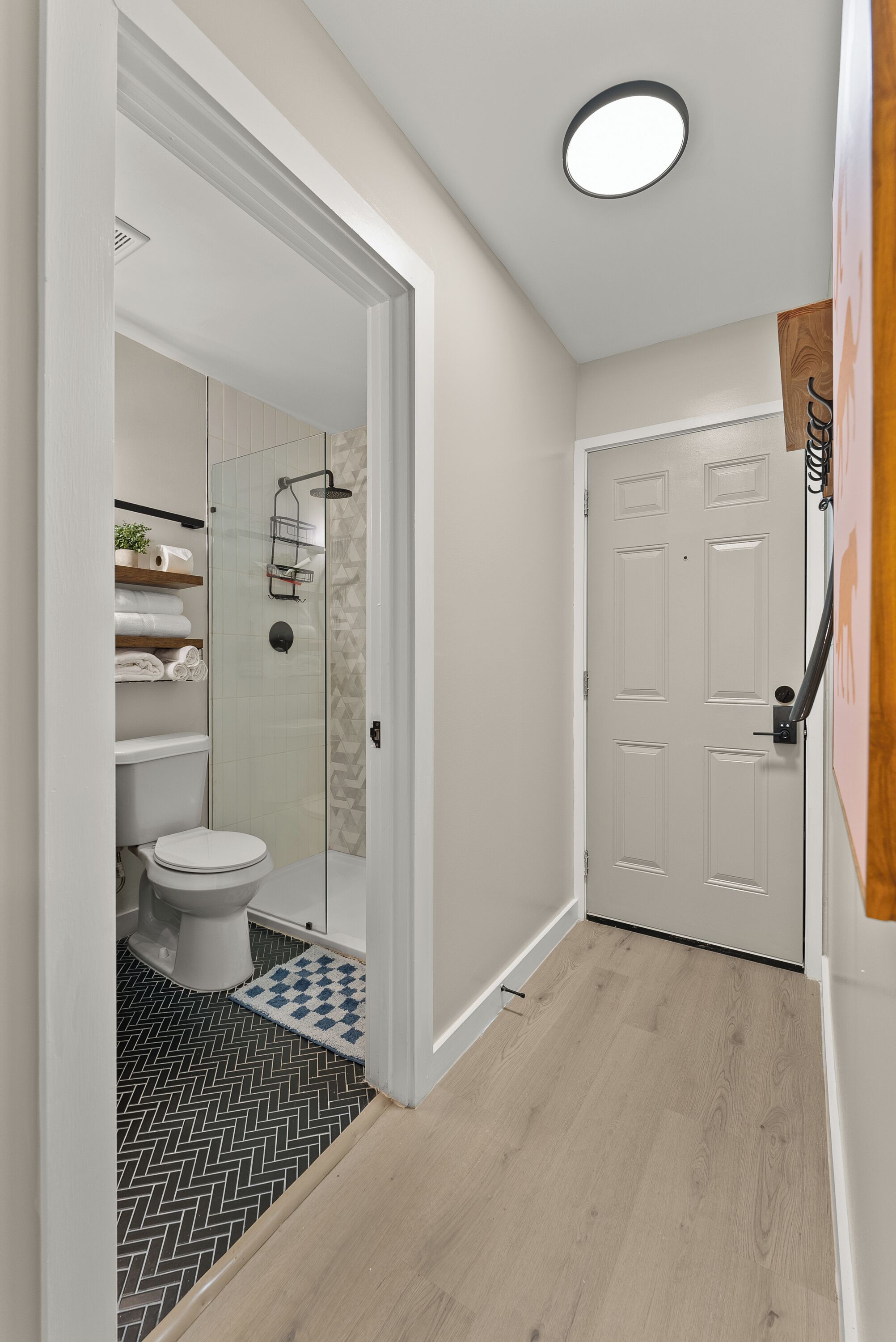 Un baño moderno con inodoro, ducha y estantes de almacenamiento.