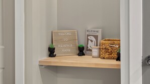 En hall med en hylla där ett välkomstskylt, en målning av Matisse och en flätad korg står.