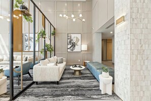 A modern lobby with a sofa, chairs, a coffee table, and a large abstract painting. - Sandman Signature Dallas Las Colinas Hotel & Suites (Irving)