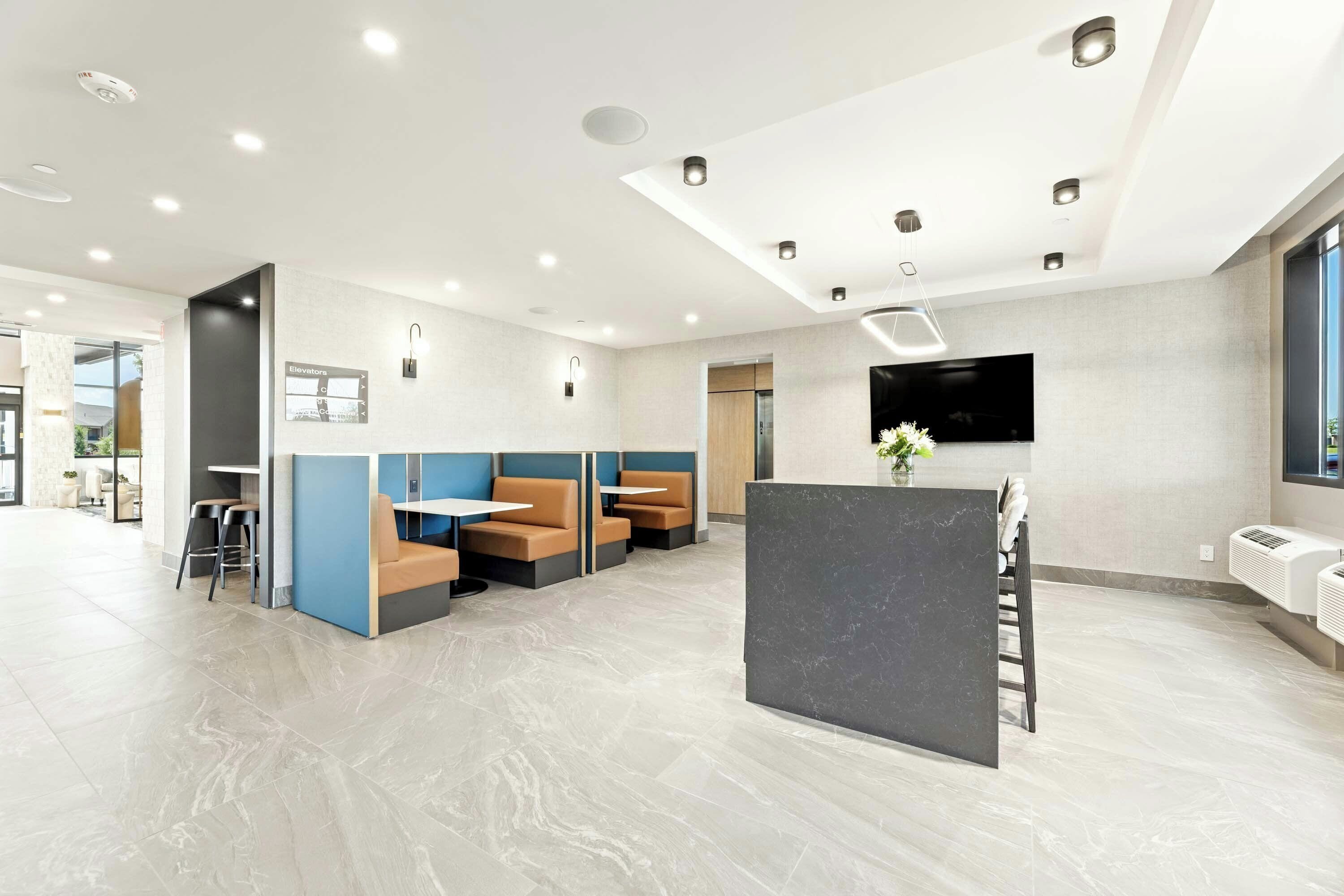 A modern interior with seating areas, a reception desk, and a mounted TV.