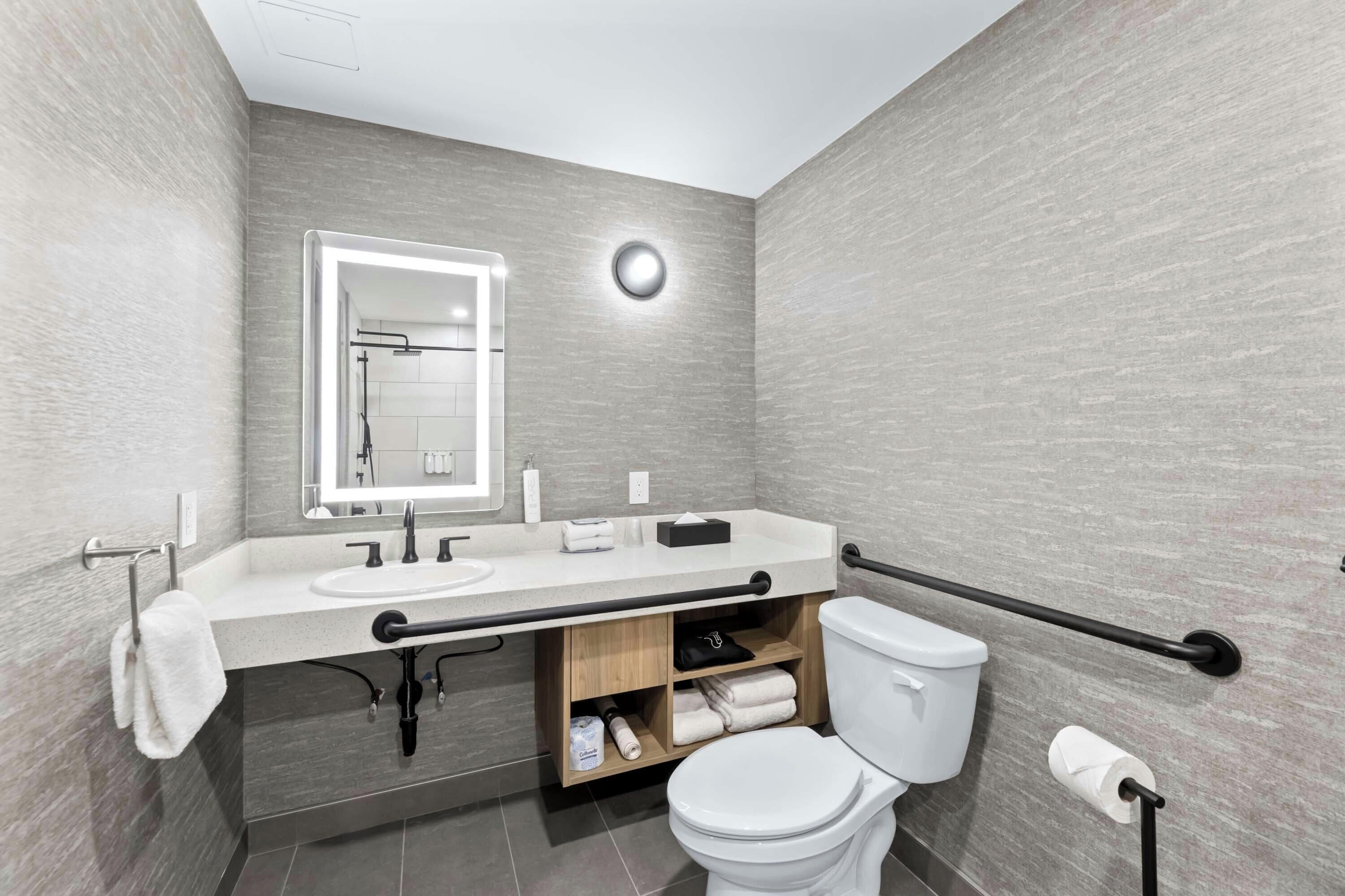 A modern bathroom with a white sink, mirror, and toilet.