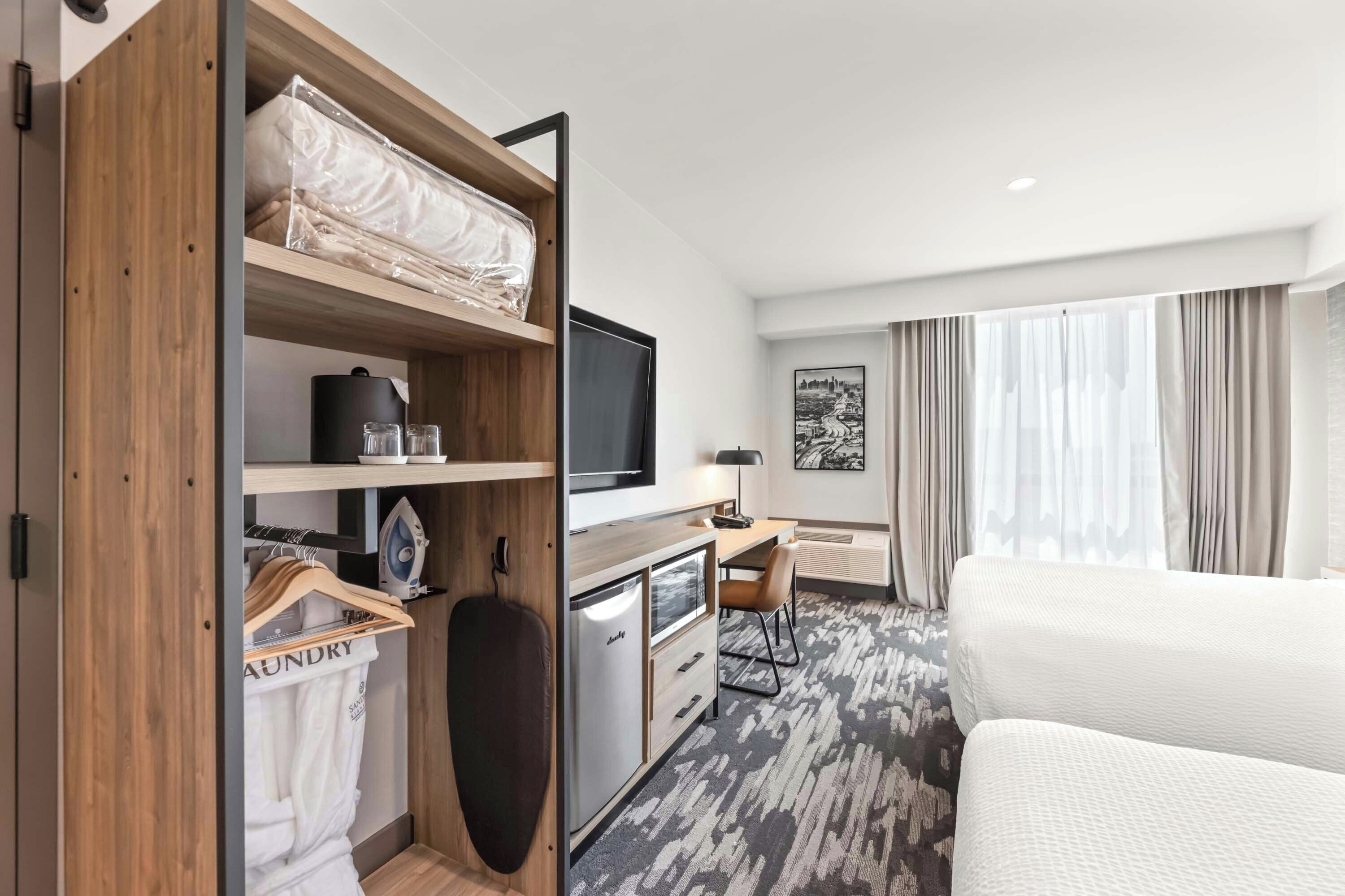 Una habitación de hotel con cama, escritorio, televisor, armario y baño.