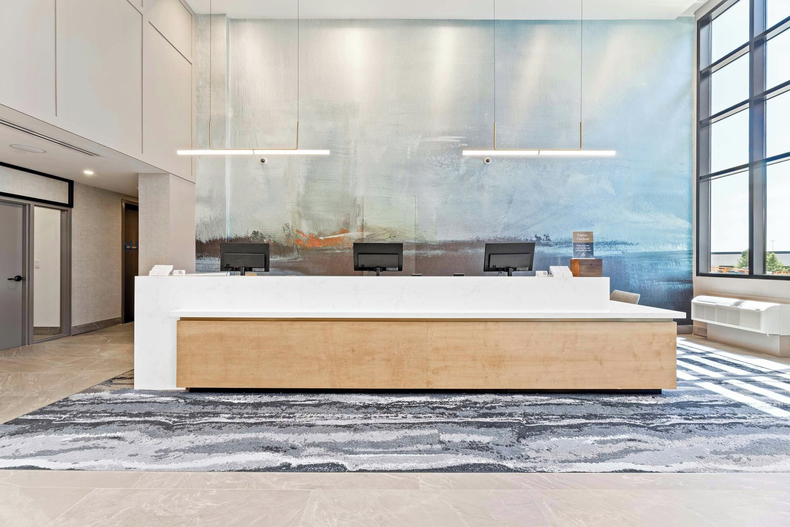 A reception area with a large window, a reception desk, and a wall mural.