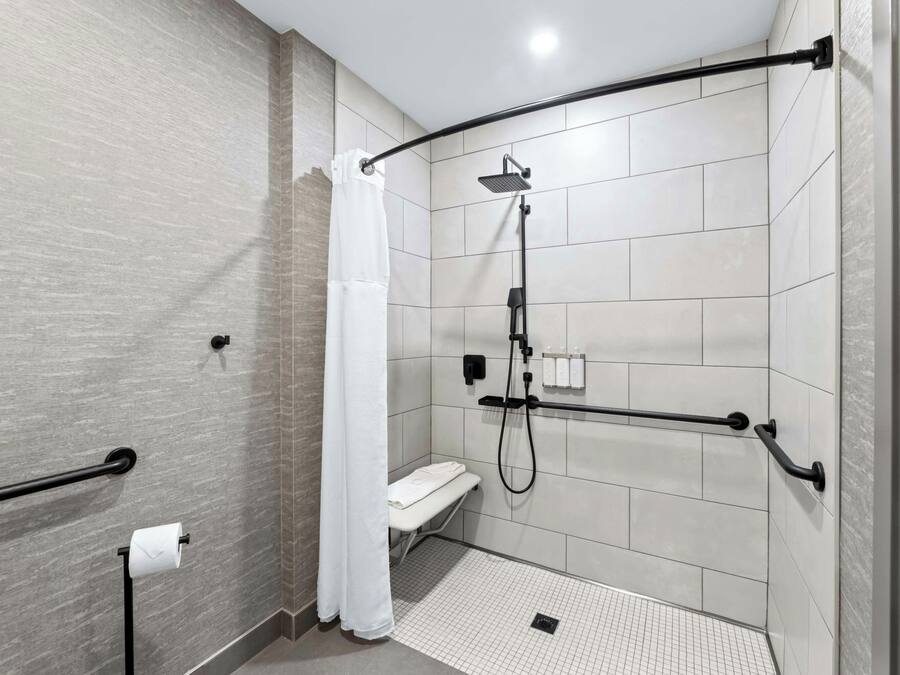 Un bagno moderno con doccia a filo pavimento, un water e un porta asciugamani.