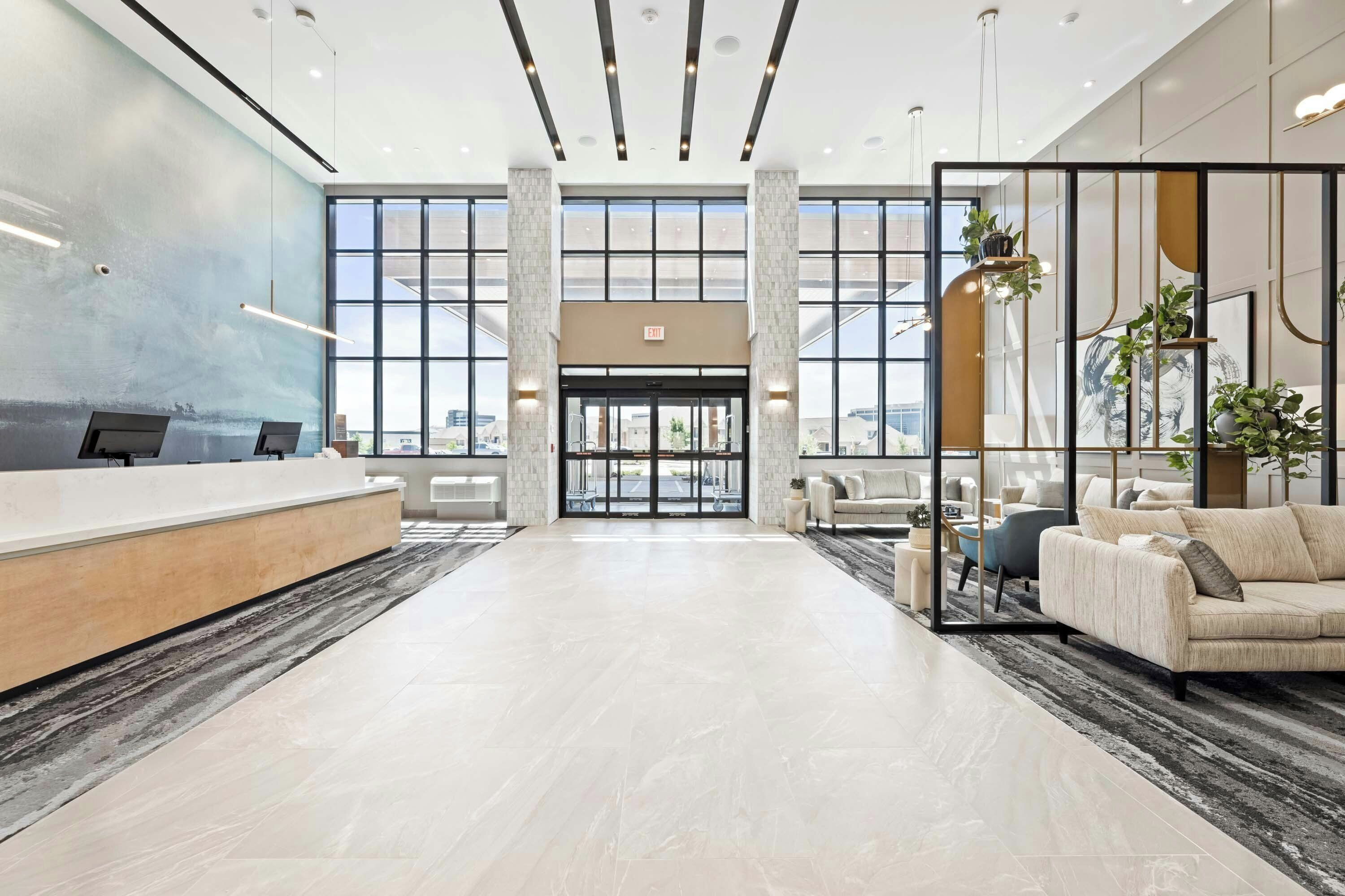 A spacious lobby with a reception desk, seating area, and large windows offering a view of the cityscape.