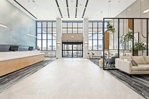 Un vestíbulo espacioso con mostrador de recepción, zona de estar y amplias ventanas que ofrecen vistas de la ciudad.