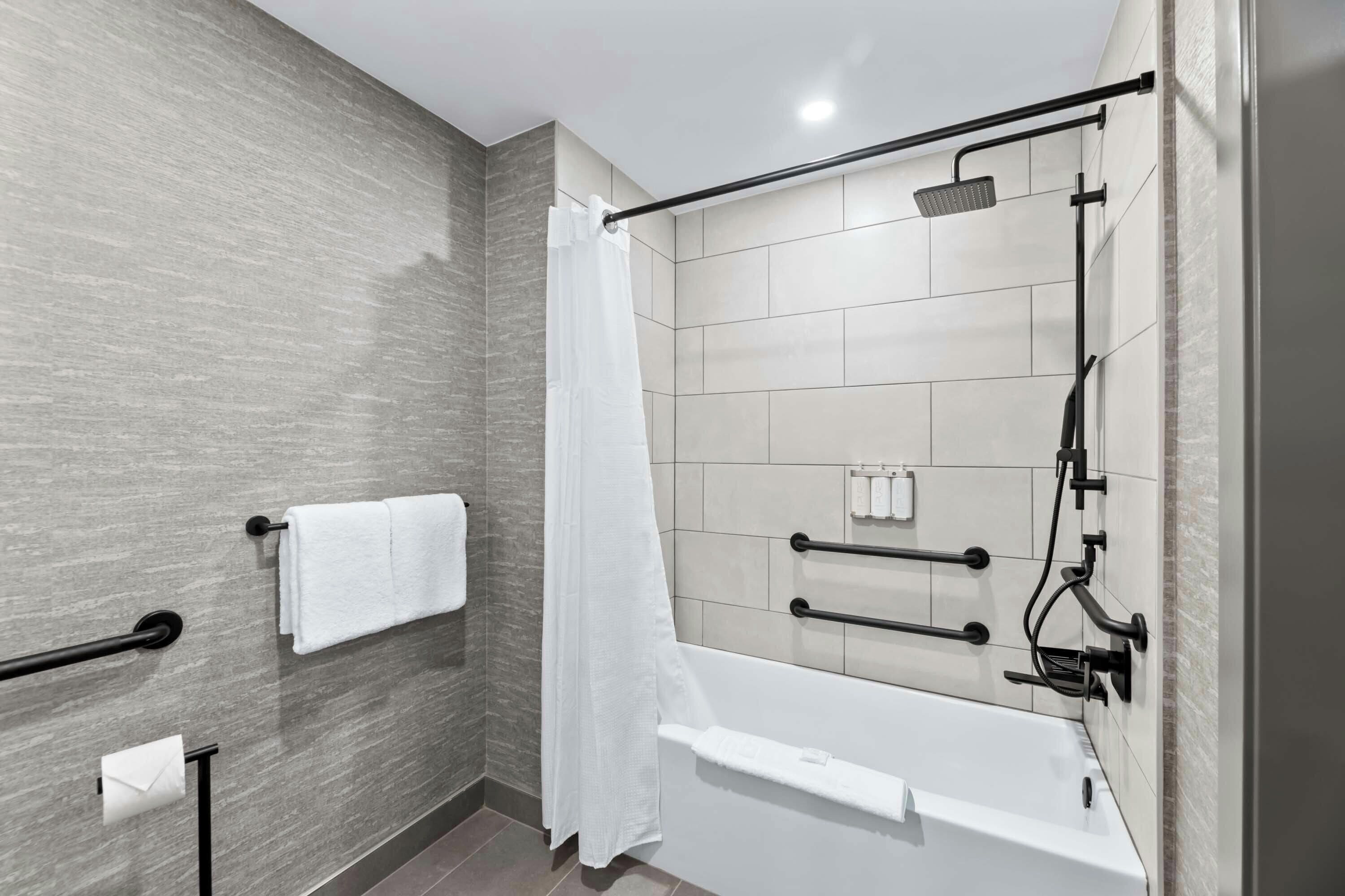 A modern bathroom with a bathtub, shower, and towel rack.