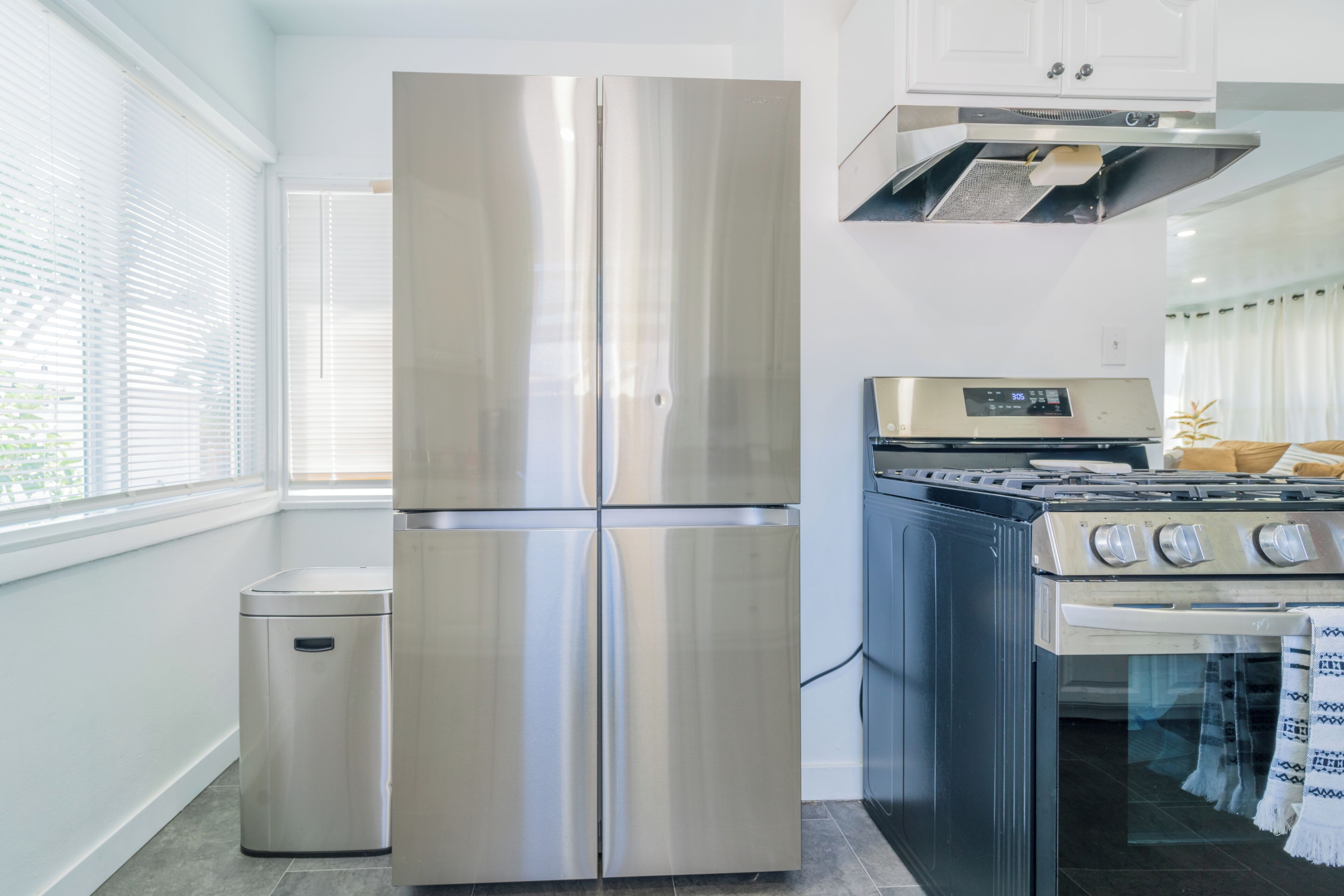 Una cocina moderna con un refrigerador de acero inoxidable, una estufa y un cesto de basura.