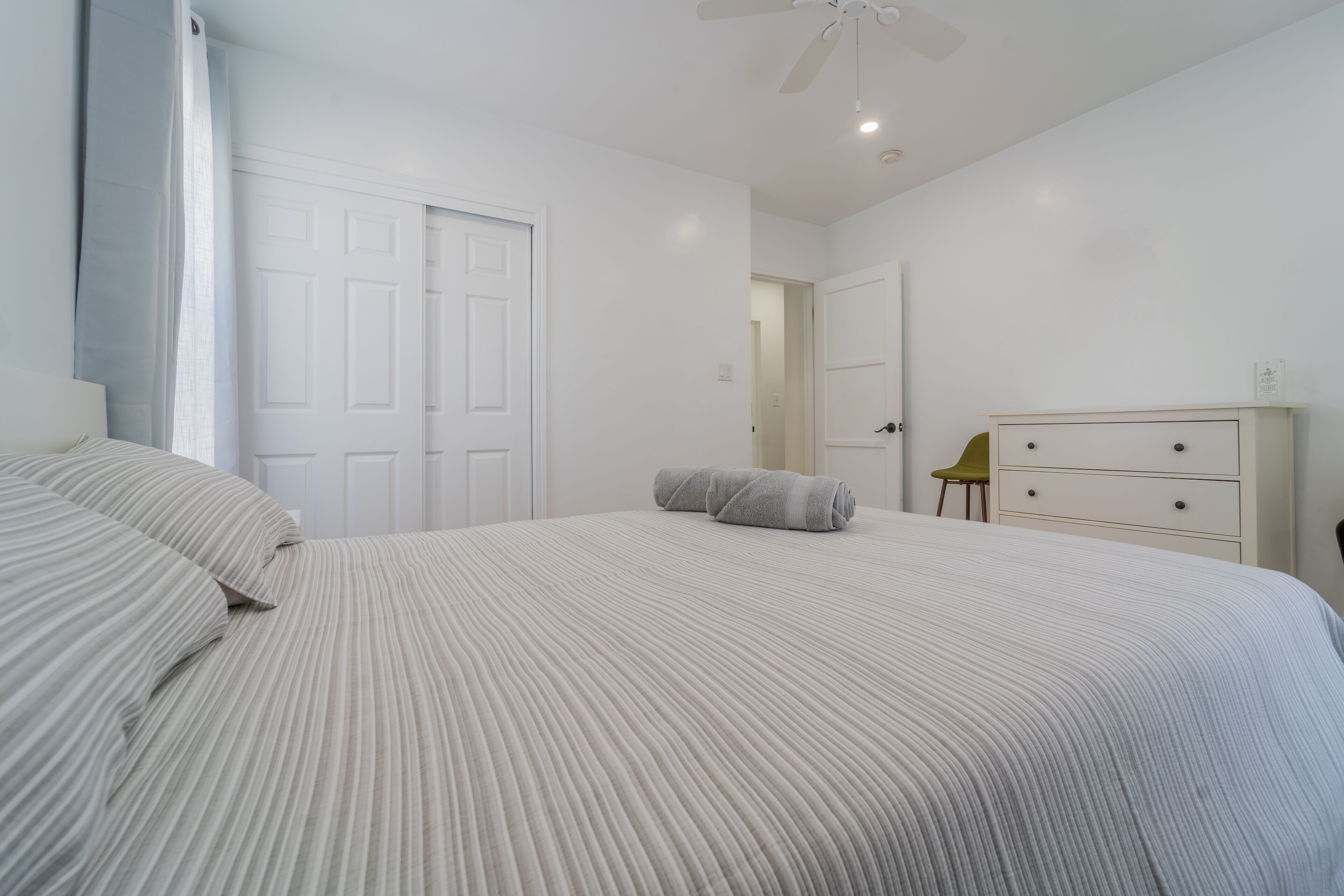A bedroom with a large bed, a dresser, and a chair.