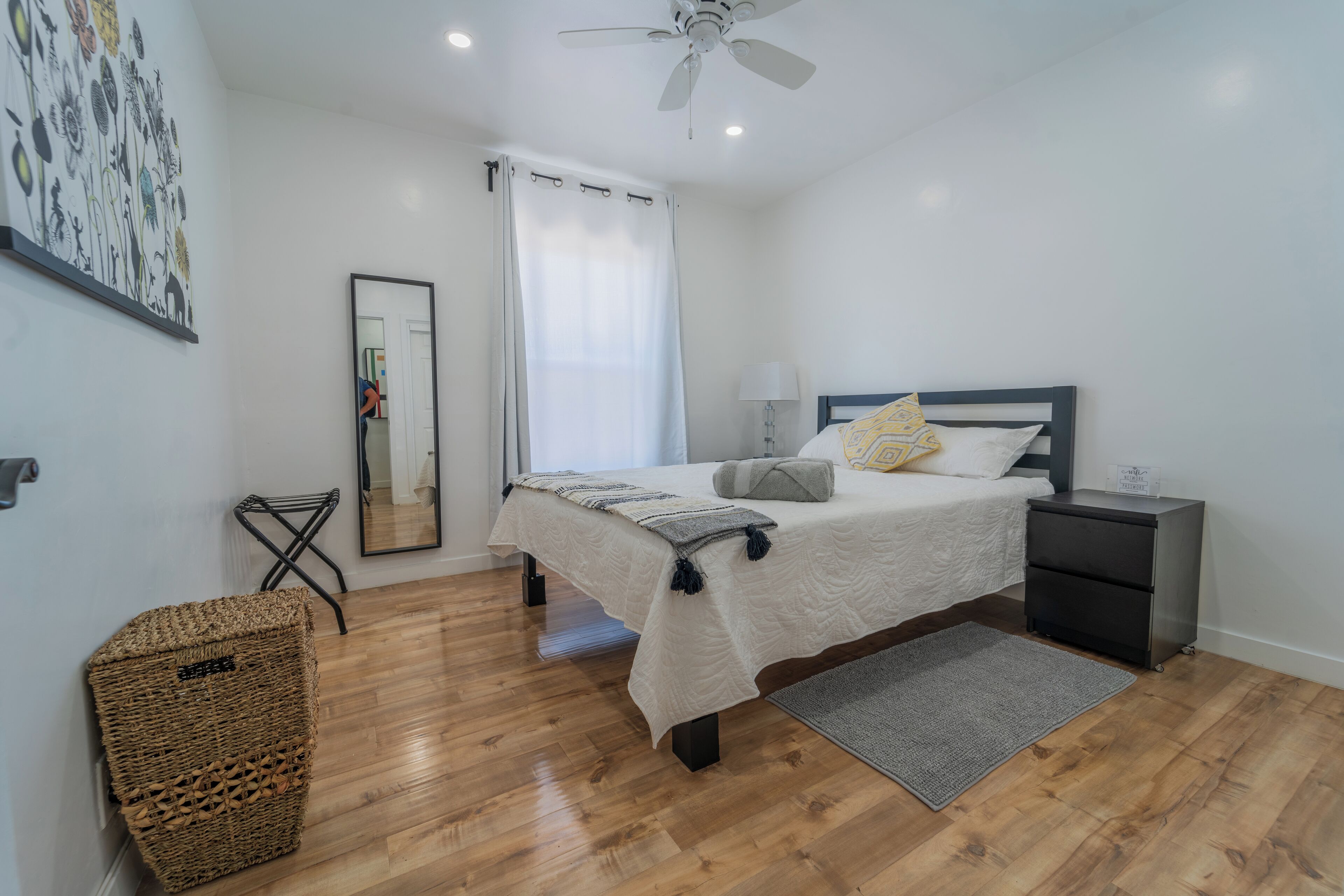 A bedroom with a bed, bedside table, nightstand, and a ceiling fan.