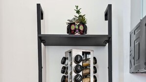 A kitchen with a black metal shelf unit holding jars, a plant, and a basket.