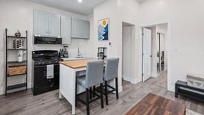 A modern kitchen with white cabinets, a black stove, and a wooden dining table with two chairs.