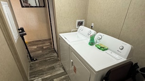 Une buanderie équipée d’un lave-linge et d’un sèche-linge à chargement frontal, d’une petite poubelle et d’un miroir au mur.