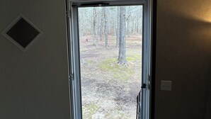 Une pièce dont la porte donne sur une zone boisée.