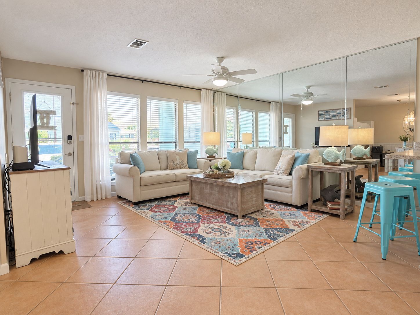 A spacious living room with a sectional sofa, a coffee table, and a dining area with stools.