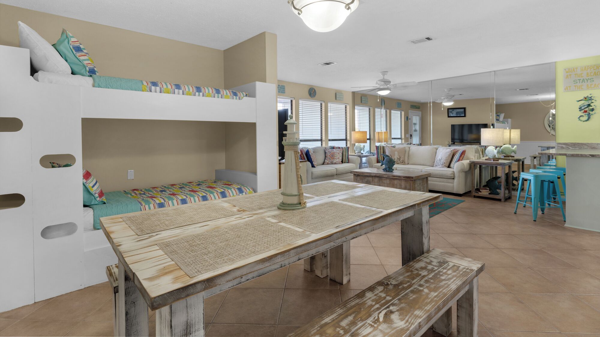 A cozy, well-lit room with bunk beds, a dining table, and a kitchen area.