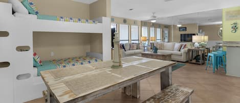 A cozy, well-lit room with bunk beds, a dining table, and a kitchen area.
