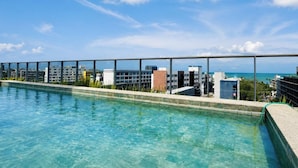 A rooftop swimming pool with a clear view of the ocean and buildings in the background. - Box 150 - LikeHome Hospedagens (João Pessoa)