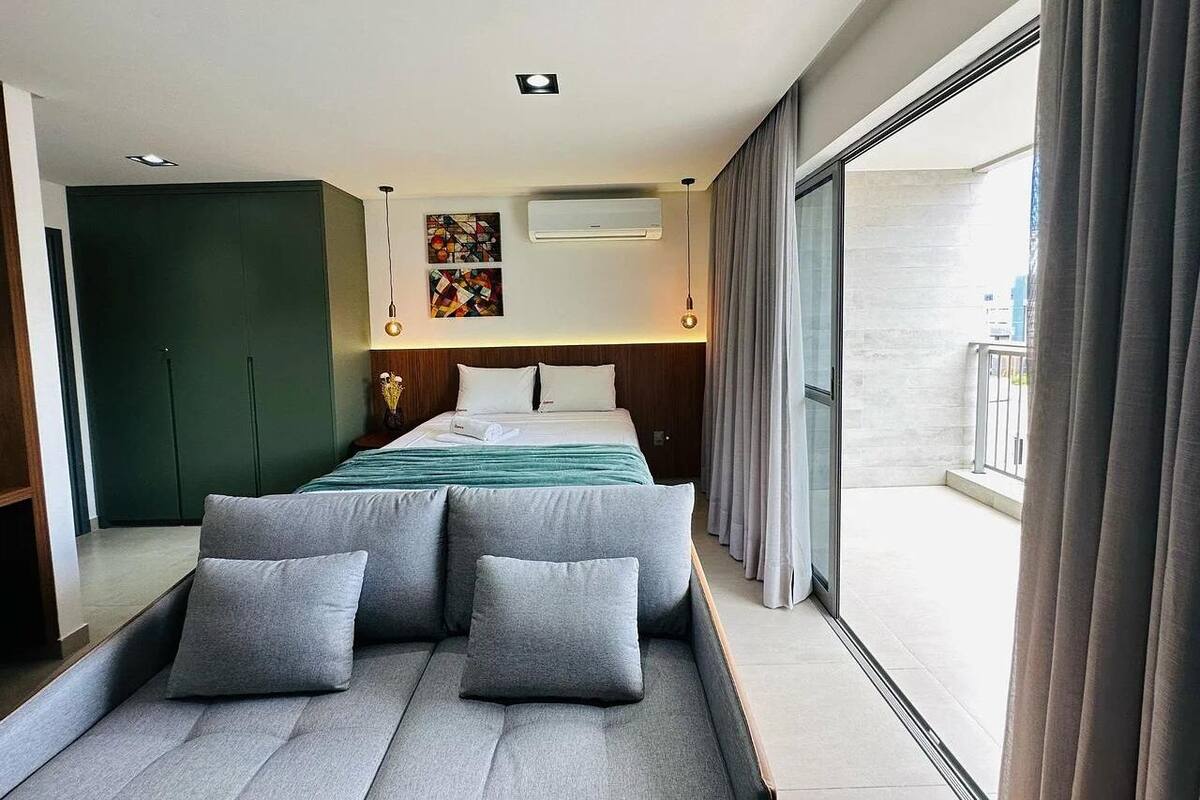 Une chambre d’hôtel moderne avec un grand lit, un canapé et un balcon agrémenté de rideaux.