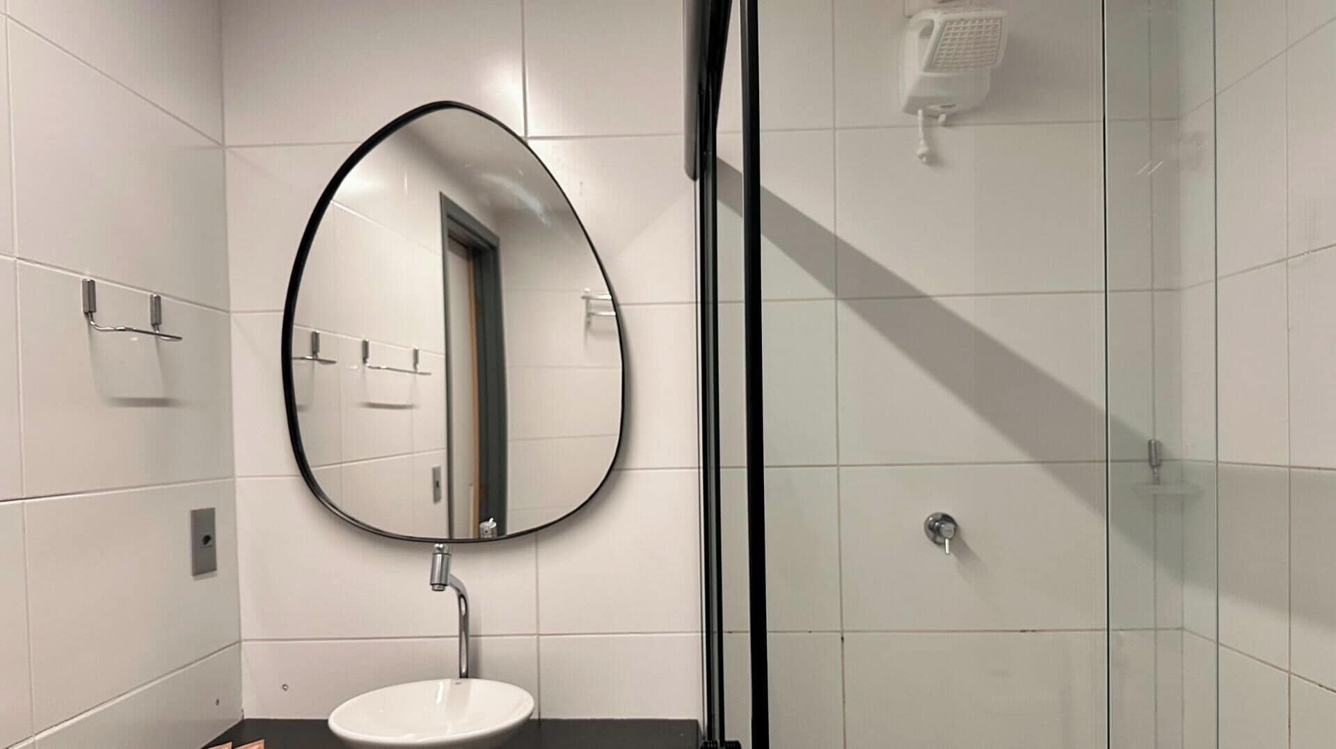 Une salle de bain moderne avec un grand miroir rond, un lavabo et une douche à parois de verre.
