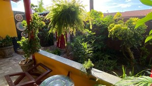A covered patio with a tiled floor, a mosaic table, and various potted plants. - Pousada Leão (Maceio)