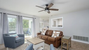 A living room with a brown leather sofa, a grey armchair, a wooden coffee table, and a ceiling fan. - Walk to Harbour Town in 5 minutes! (Hilton Head Island)