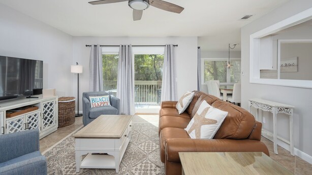 A modern living room with a brown leather sofa, a white coffee table, and a TV on a cabinet. - Walk to Harbour Town in 5 minutes! (Hilton Head Island)